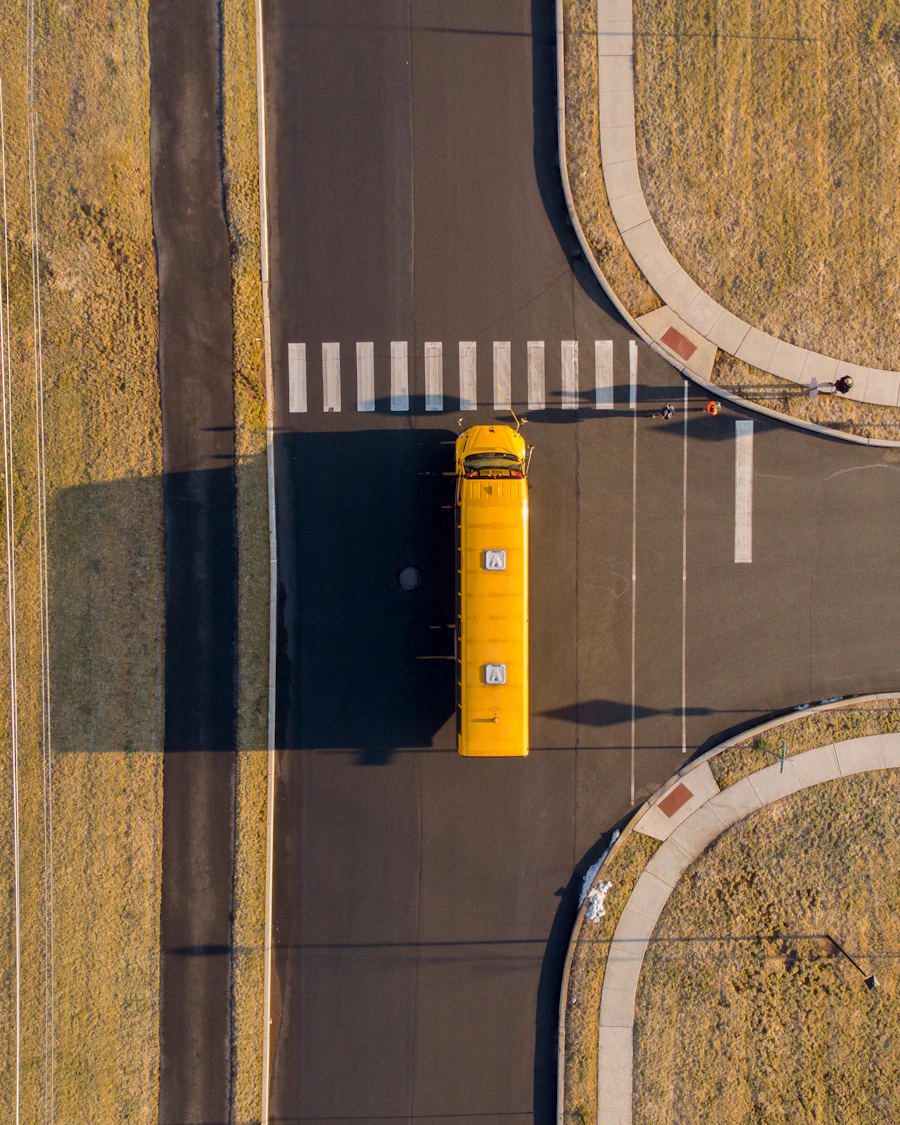 A school bus seen from directly overhead, stopped at a crossing on a quiet road.